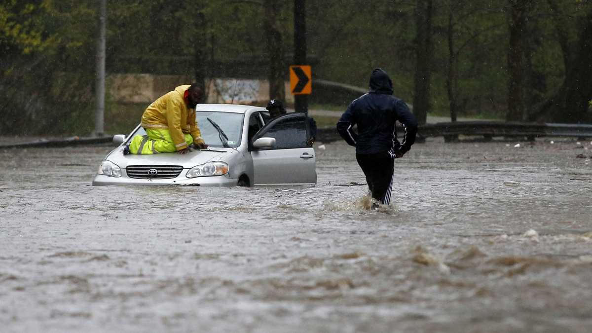  A man walks across a flooded section of the Cobbs Creek Parkway as a tow truck worker tries to free a swamped car, Wednesday, April 30, 2014, in Philadelphia. (AP Photo) 