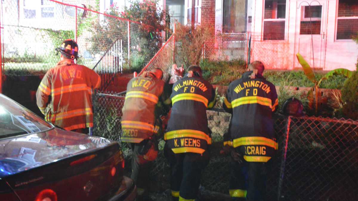Firefighters rest on a fence outside the home where Wilmington firefighters were killed in September 2016. (John Jankowski/for NewsWorks)