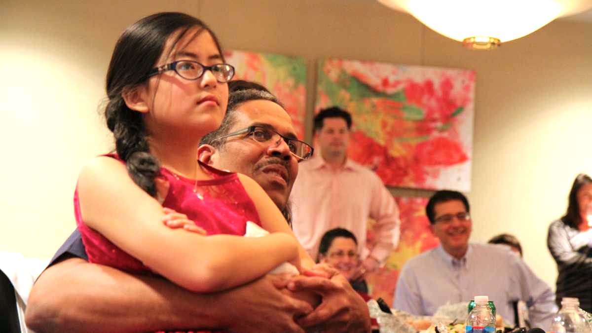  Jim Lewis of Chester County, Pa., holds his daughter, Laura, as they watch his TV appearance on the hit show, Shark Tank. (Zack Seward/WHYY) 