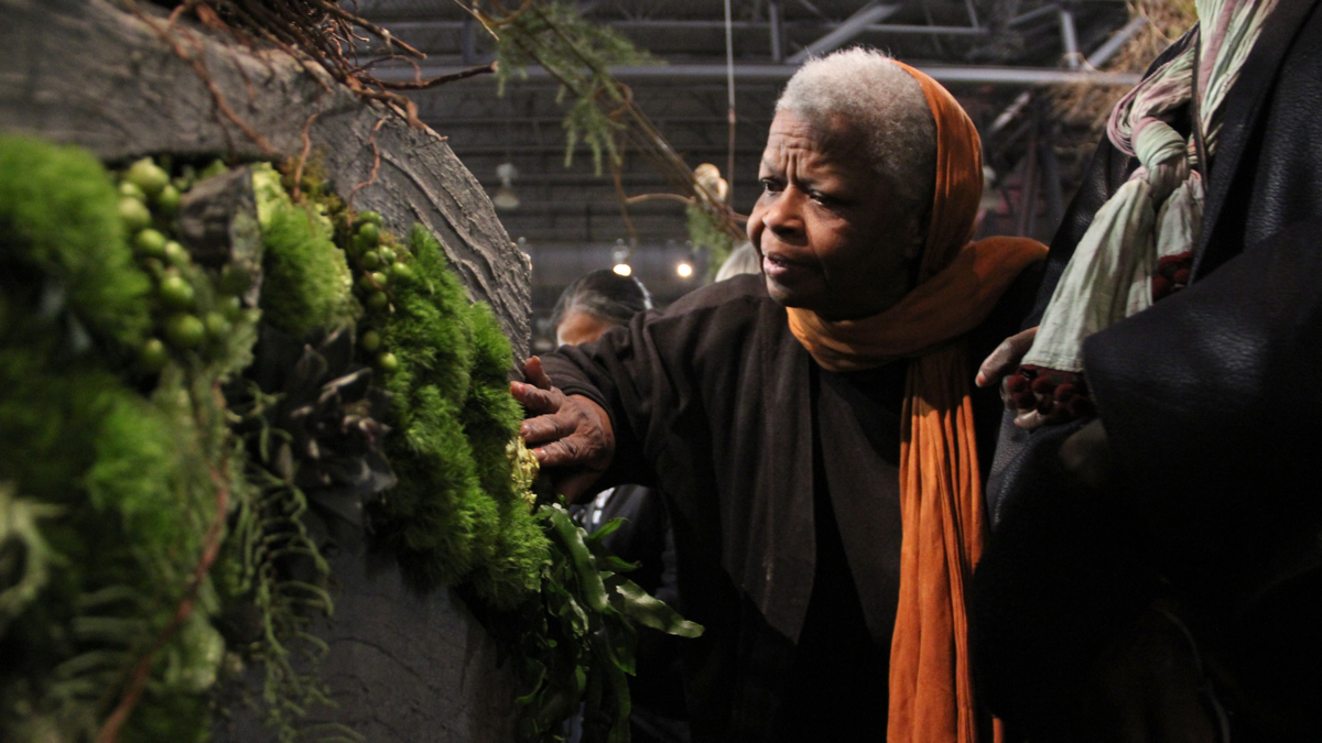 Eleanor Childs runs her fingers along a moss-covered wall during a tour for the blind at the Philadelphia Flower Show. (Emma Lee/WHYY)