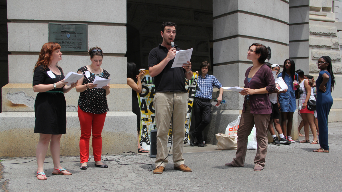 Actor Seth Schmidt-Hall reads from the script of 'School Play' at City Hall, where Council was holding hearings about school funding. Six near-simultaneous readings took place at courthouses in eastern Pennsylvania. (Emma Lee/WHYY)