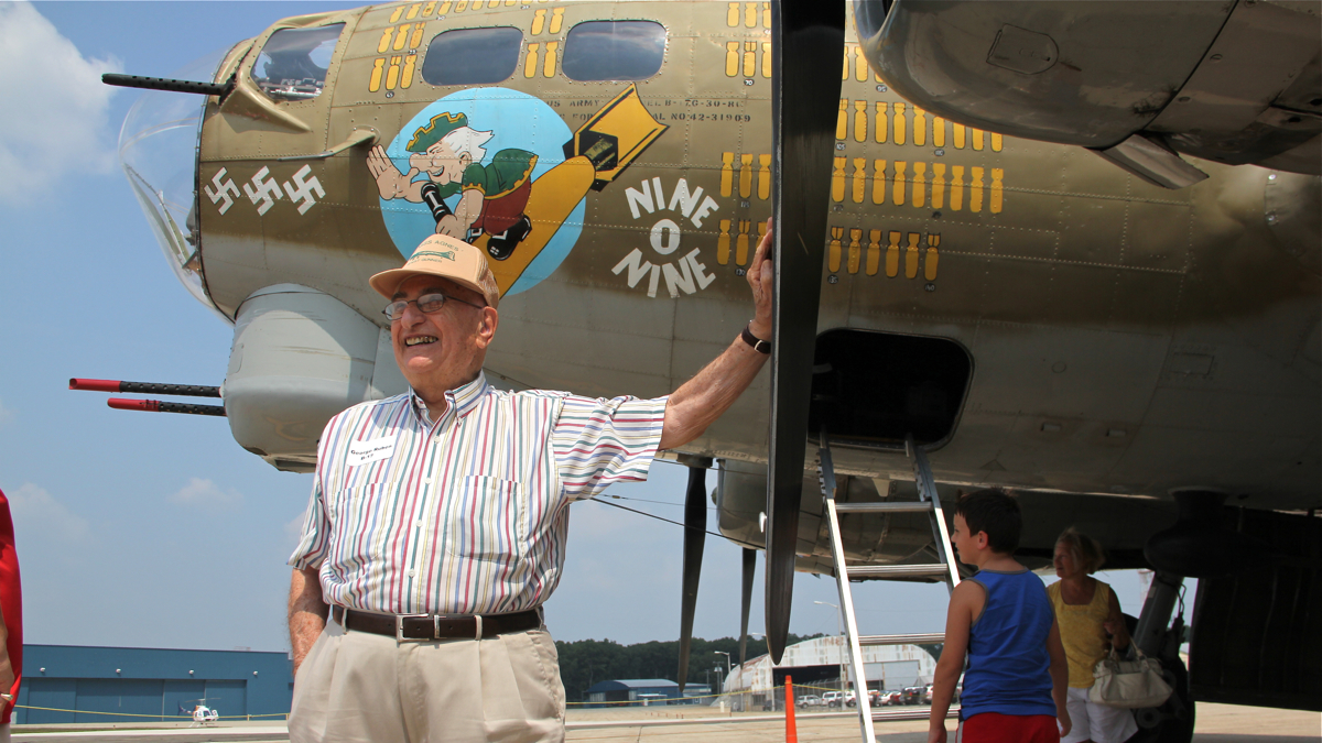 World War II gunner George Rubin stands beside the Nine O Nine B-17 Flying Fortress at Millville Army Air Field Museum. (Emma Lee/WHYY)
