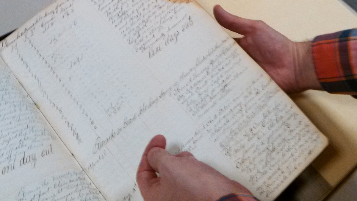 Craig Bruns of the Independence Seaport Museum flips through an old weather log book. (Kimberly Haas/for The Pulse)