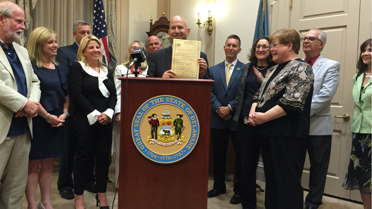 Governor Jack Markell (center) holds a signed piece of legislation after the final day of the General Assembly. (Avi Wolfman-Arent
