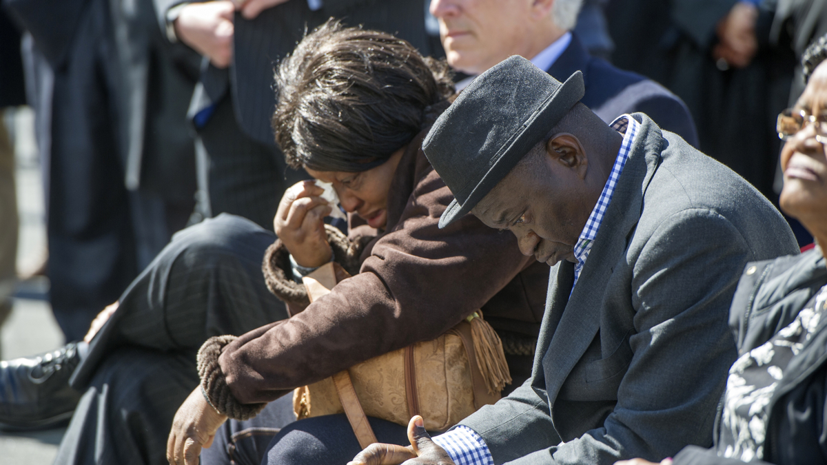 Building collapse victim Roseline Conteh's sister, Kadie Conteh, and husband, Aiah Boya, listen to speakers during the groundbreaking. (Jonathan Wilson for NewsWorks)