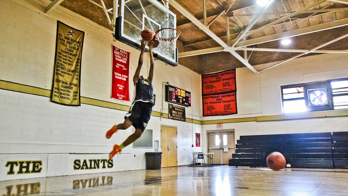 A member of the Neumann-Goretti girls' basketball team makes a 360 degree dunk shot at Tuesday's practice. (Kimberly Paynter/WHYY)