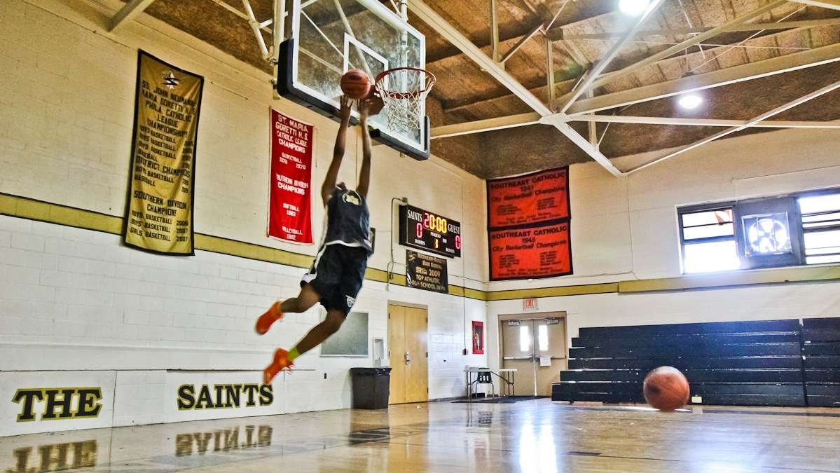  A member of the Neumann-Goretti girls basketball team makes a 360-degree dunk shot at practice. (Kimberly Paynter/WHYY) 