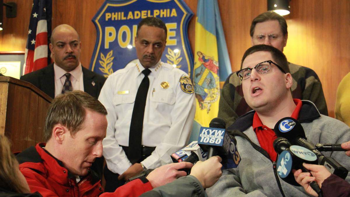 Joe Jaskolka (right), who was shot in the head by a stray bullet on New Year's Eve, 1998 when he was 11 years old, tells reporters about his struggles in an effort to discourage Philadelphians from firing guns in celebration of the New Year. (Emma Lee/WHYY)