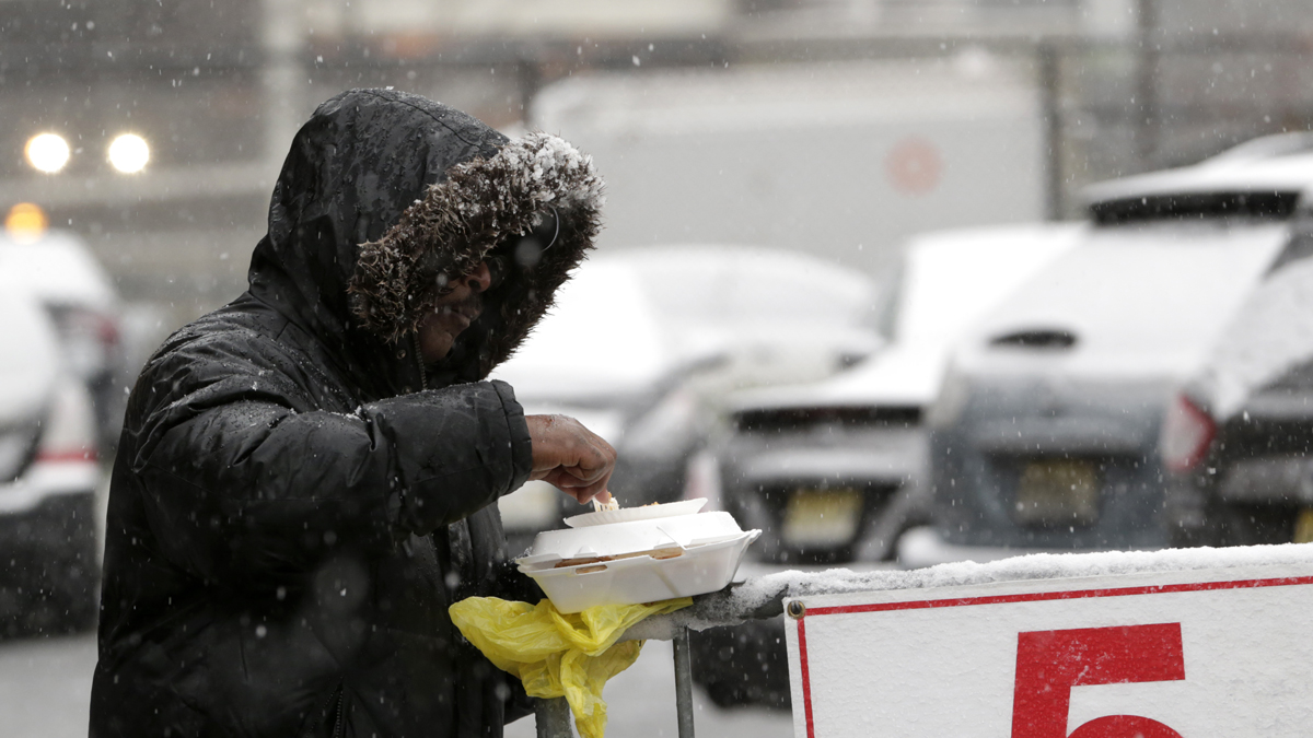 Snow falls over a homeless person in Newark