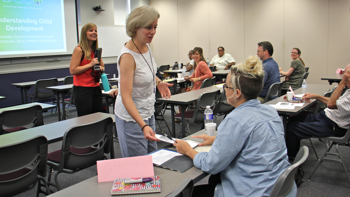 Professional development specialist Nora Connell hands out materials during a class for prospective substitute teachers at Delaware County Intermediate Unit. (Emma Lee/WHYY)