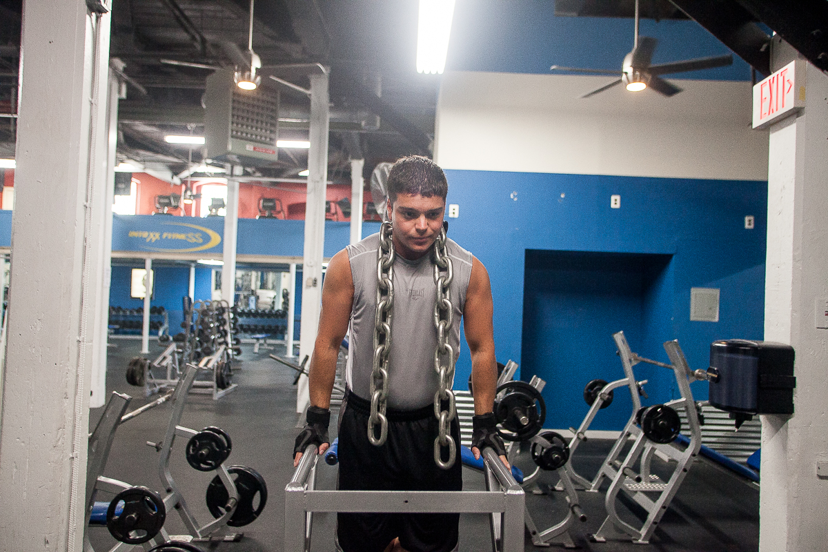 Gym manager Sam DeMarco demonstrates a weighted dip exercise at Intoxx Gym in Manayunk. (Brad Larrison/for NewsWorks)