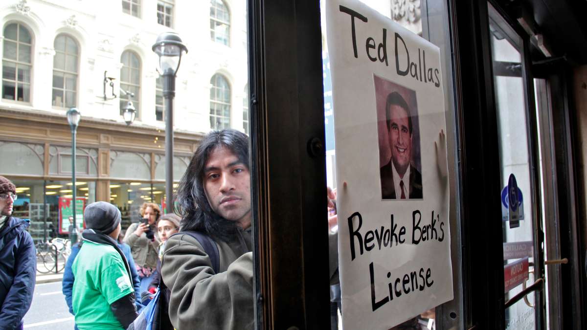  Juntos volunteer Drew Morrissey presses his poster against the door at 801 Market St. after he and other protesters were asked to leave the building. Ted Dallas is the Pennsylvania Secretary of Human Services. (Emma Lee/WHYY) 