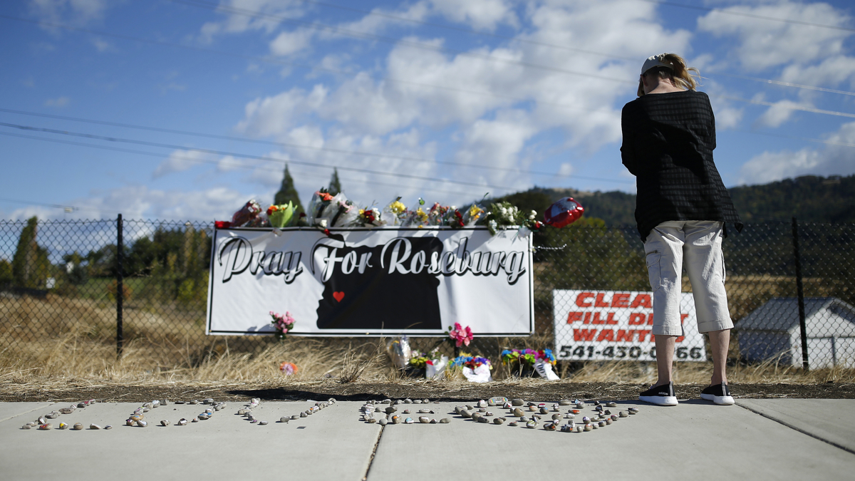  A woman visits a makeshift memorial near the road leading to Umpqua Community College Saturday, Oct. 3, 2015, in Roseburg, Ore. Armed with multiple guns, Chris Harper Mercer, 26, walked in a classroom at the community college, Thursday, and opened fire, killing several and wounding several others. (AP Photo/John Locher) 