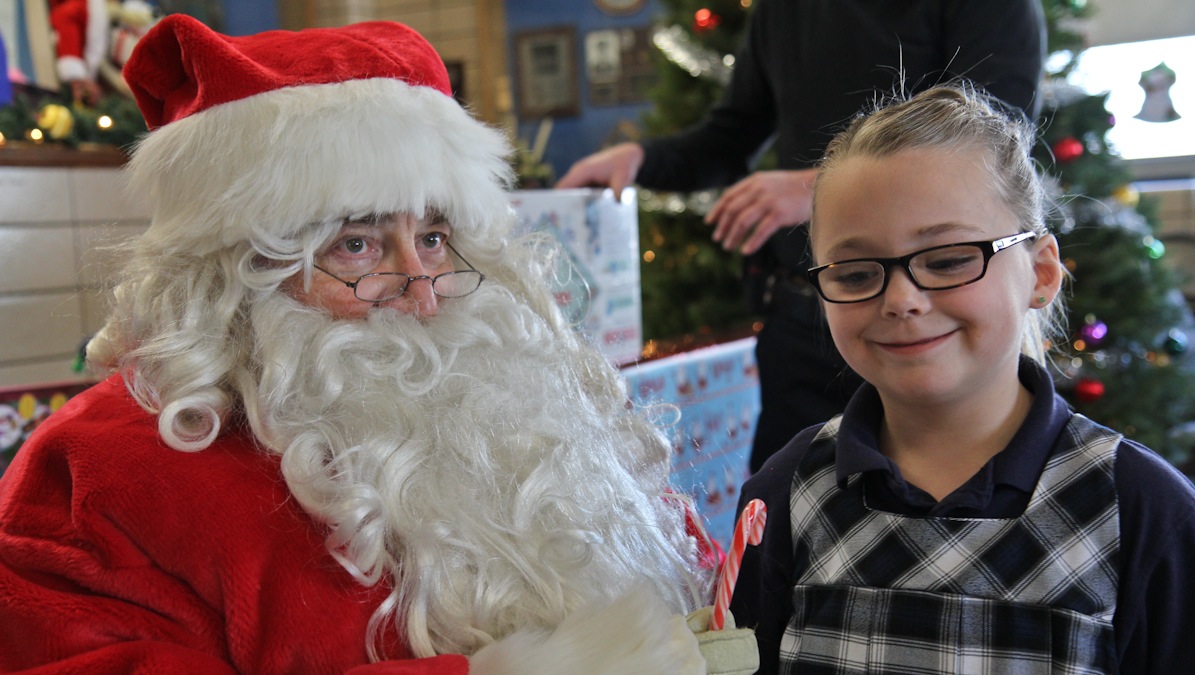 Riley Fitzpatrick asks Santa for a puppy at the 5th District Police Station Annual Christmas party. (Kimberly Paynter/WHYY)