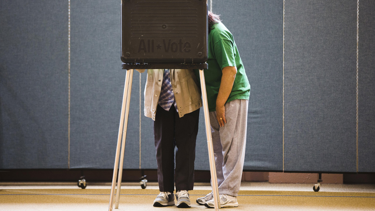  Voting machine operator George Stuski reads a newspaper as people cast their votes at the Mummer Museum in Philadelphia, Pa.  (AP Photo/ Joseph Kaczmarek) 