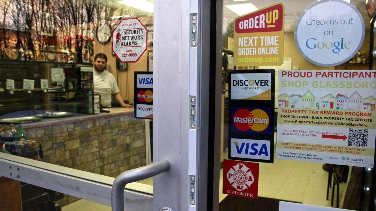  Filippo Sparacio stands behind the counter at Filippo's Pizza in Glassboro. He says the town's property tax reward program is good for business. (Emma Lee/WHYY) 