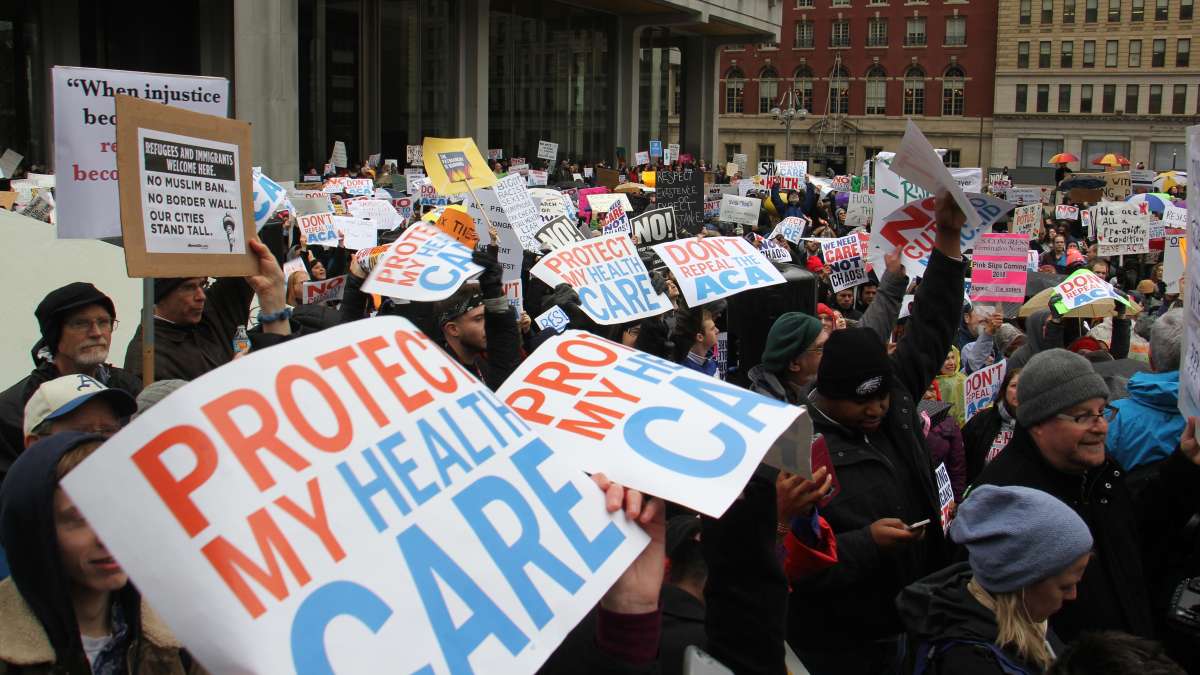 Protesters gather at Thomas Paine Plaza on Thursday afternoon under a steady drizzle. (Emma Lee/WHYY)
