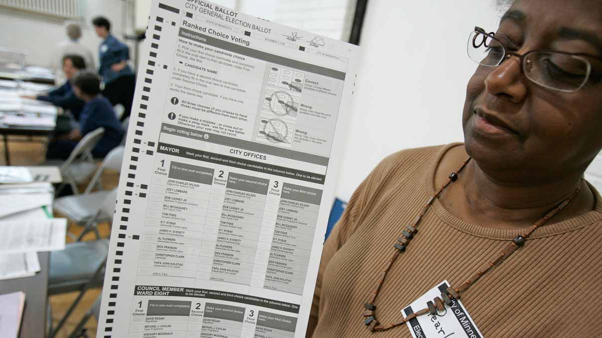 An election judge holds up a general election ballot featuring new ranked choice voting
