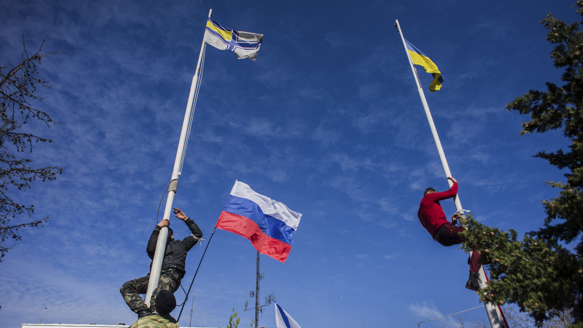  Members of the Crimean pro-Russian self-defense forces climb up to remove a Ukrainian flag, right, and a Ukrainian navy flag, left, at the Ukrainian navy headquarters in Sevastopol, Crimea, Wednesday, March 19, 2014. In center is a Russian flag. (AP Photo/Andrew Lubimov) 