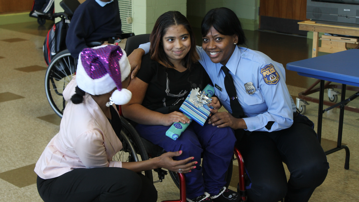  Widener Memorial School student Alicia Rodriguez receives a gift from 35th District Community Relations Officer Roslyn Downing. (Matthew Grady/for NewsWorks) 