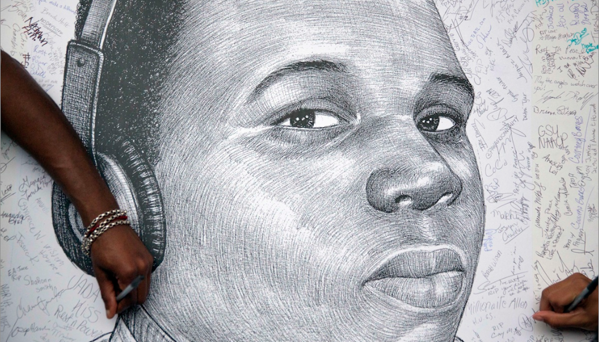  Protestors autograph a sketch of Michael Brown during a protest, in Atlanta. Michael Brown Jr. was on the verge of starting college, eager to launch himself into the adult world. Instead, on Monday he’ll be mourned at his funeral, more than two weeks after his fatal shooting by a white police officer. (AP Photo/David Goldman, File) 