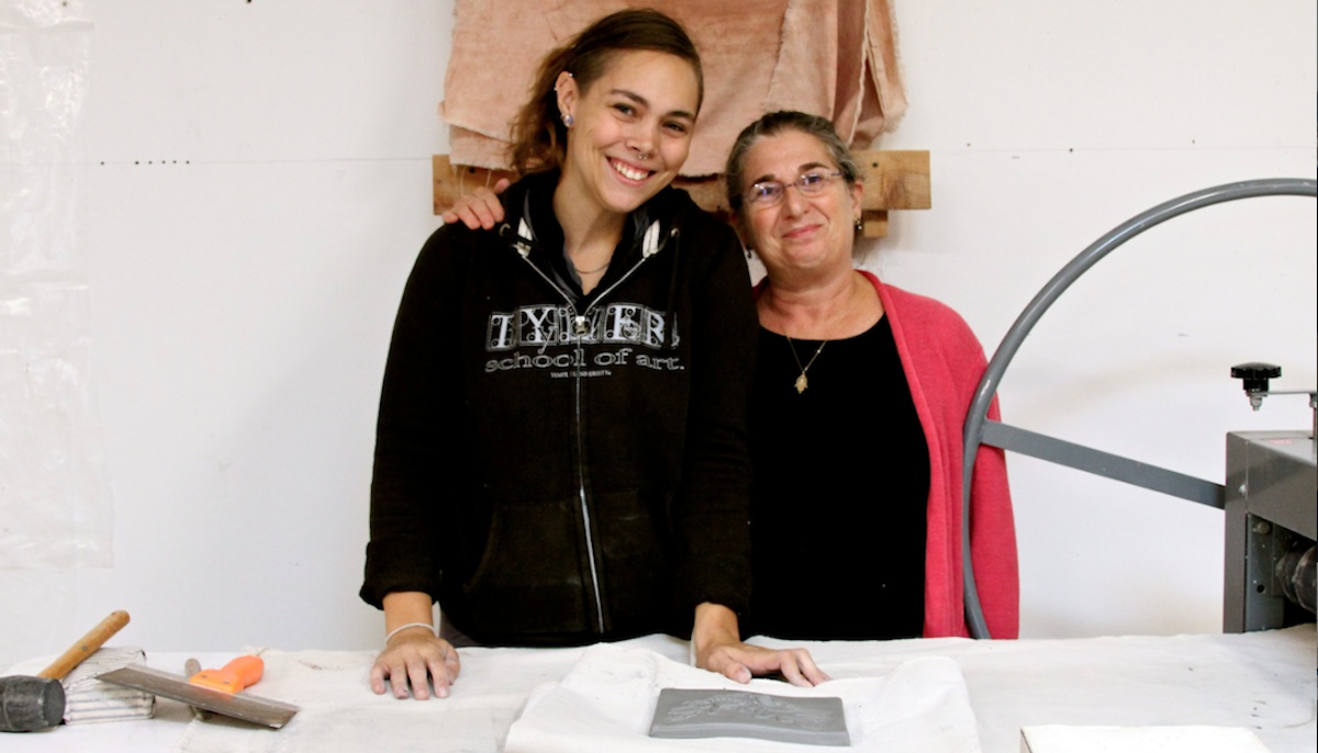 (L-R) Production manager Rachel Sooy and art director Karen Singer stand behind the press where clay is flattened in their studio on East Church Lane in Germantown. (Lauren Gruber/for NewsWorks)  
