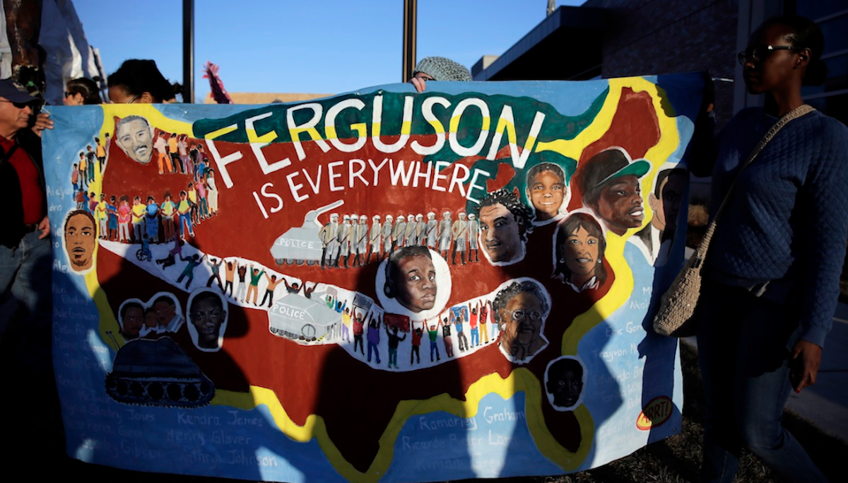 People hold up a sign during a protest outside the Ferguson (Mo.) Police Department on Monday. Protesters marched several miles through Ferguson to the police department from the site where Michael Brown was killed this past summer by a police officer. (AP Photo/Jeff Roberson) 