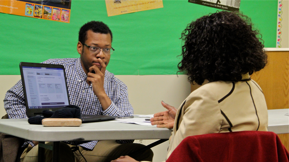 Will Bethea of Pennsylvania Health Access Network counsels a prospective enrollee during a sign-up session at the Coleman Library in Northwest Philadelphia. His group has helped nearly 400 people enroll in Medicaid since eligibility expanded in the state. (Emma Lee/WHYY)