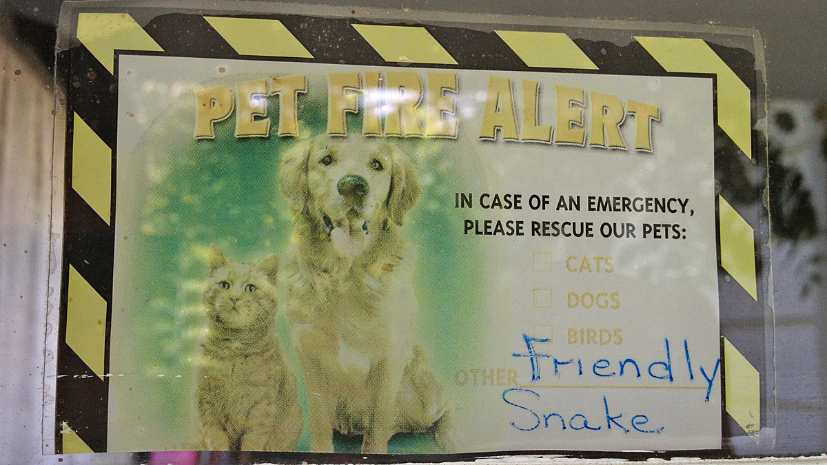  A sign on the front door of Snakey's house lets emergency workers know that the boa constrictor is not a threat. (Zack Seward/WHYY) 