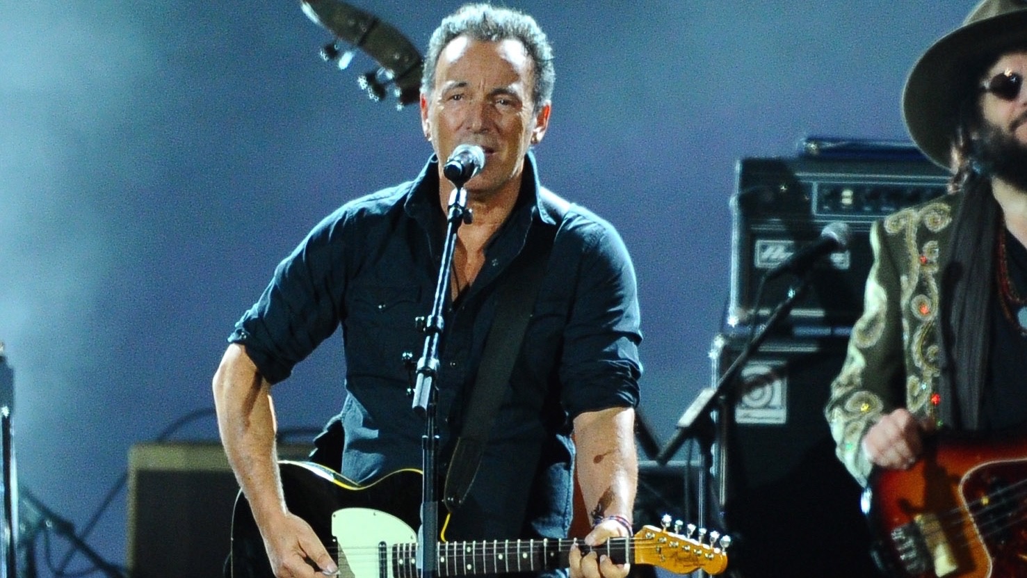 Bruce Springsteen plays a guitar on stage.