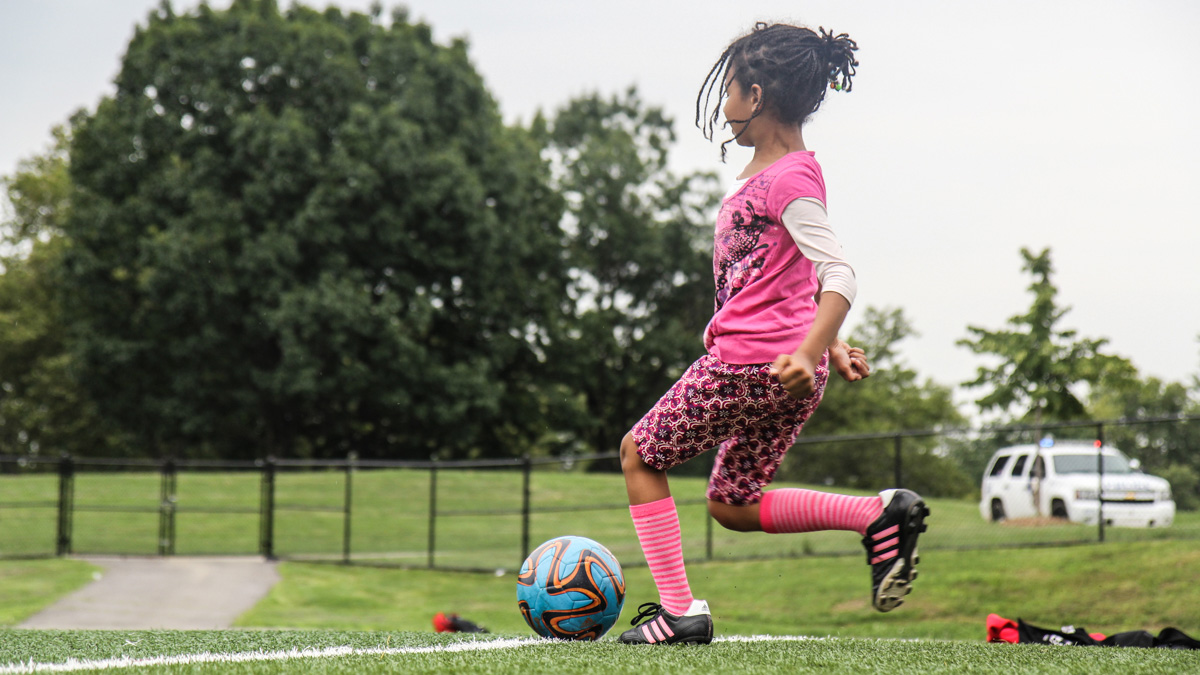 A camper attempts to make a goal at Starfinder Soccer camp on the astroturf field in Hunting Park. (Kimberly Painter/WHYY)