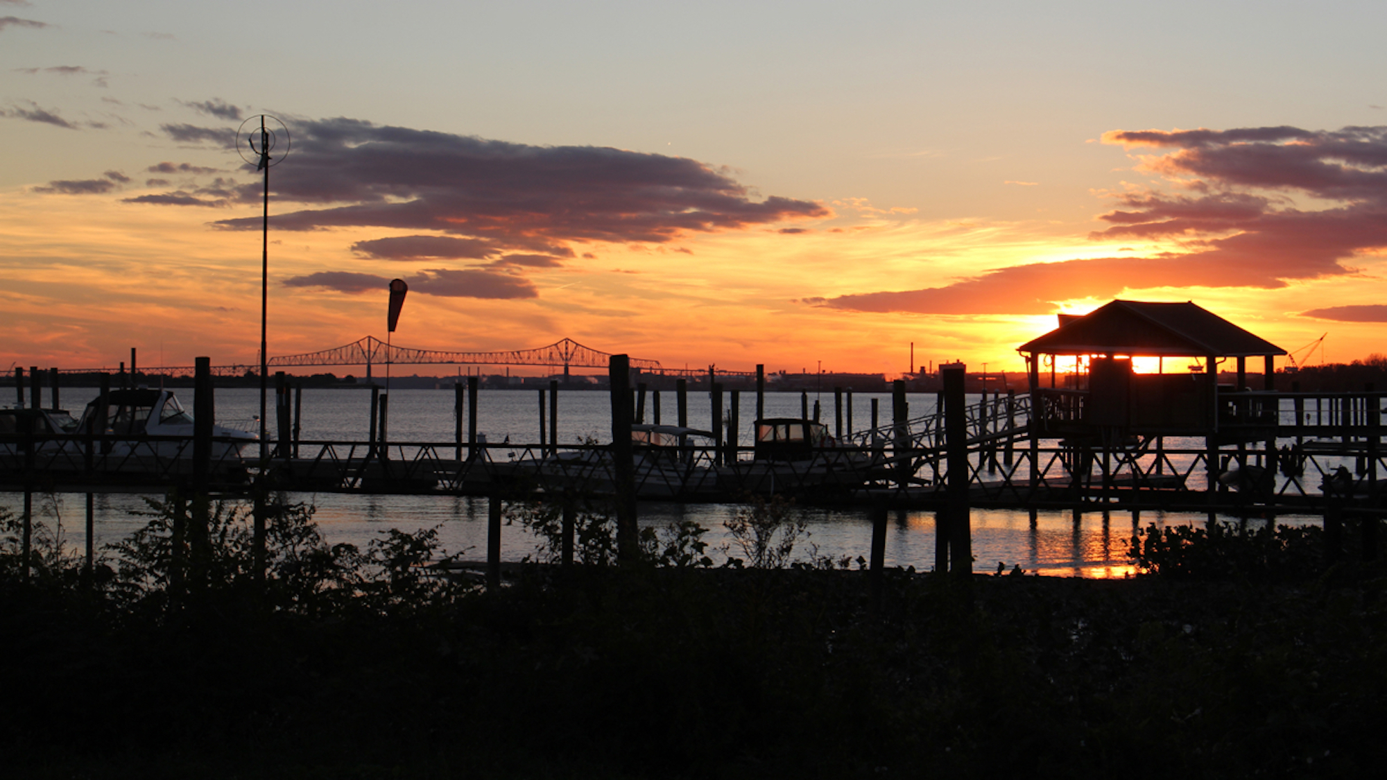The sun sets behind the docks at the Riverside Yacht Club on the Delaware River in Tinicum. (Emma Lee/WHYY)