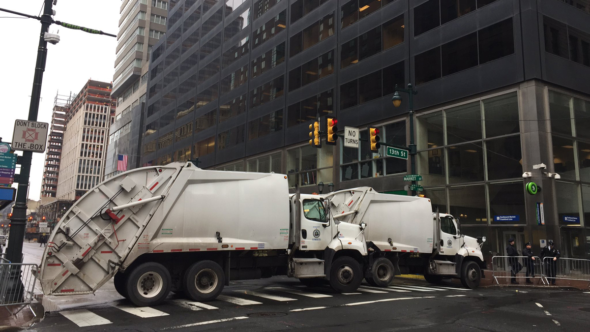 Trash trucks are shown blocking Market Street outside of the GOP congressional retreat where President Trump will visit. (Dana DiFilippo/WHYY)