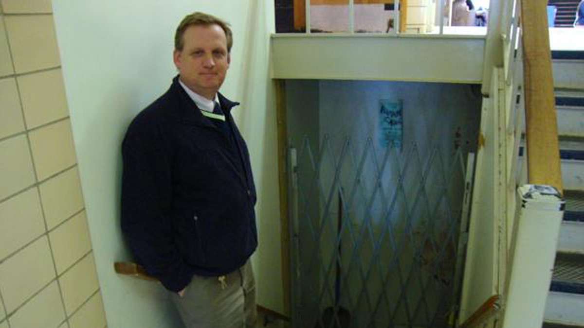  State High dean of students, Chris Weakland, stands next to the entrance to storage space under the auditorium stage. It's gated because of flooding and mold.(Emily Reddy for WPSU) 