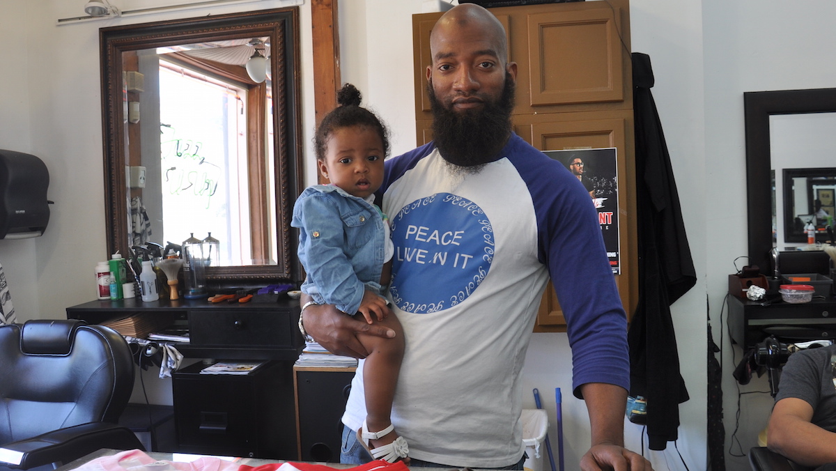  Will Little sells most of his shirts at Jazz U Up in South Philly. On his shoulder is his daughter, Sophia. (Greta Iverson/for NewsWorks) 