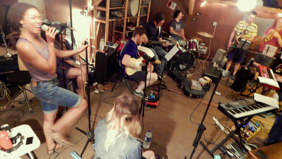 Imani Roach is shown singing with the band at a rehearsal