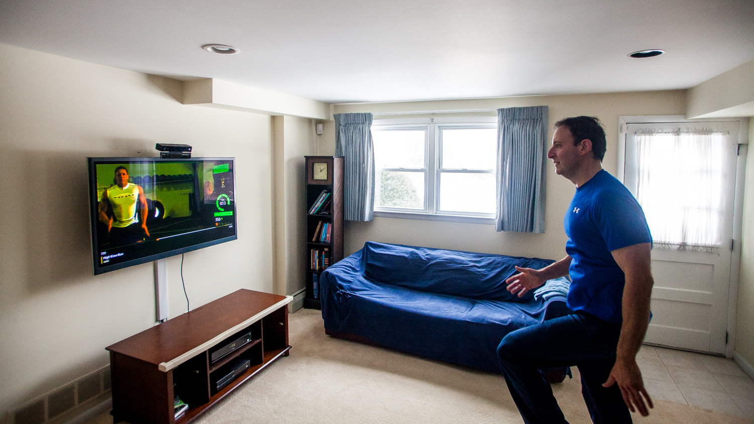 Dr. Paul Ballas works out with XBOX Fitness following  along with the moves of simulated NFL Players and P90x creator, Tony Horton. Dr. Ballas attributes his dramatic weightloss of 60 lbs. to his regular use of the XBOX game.  (Brad Larrison/for NewsWorks)