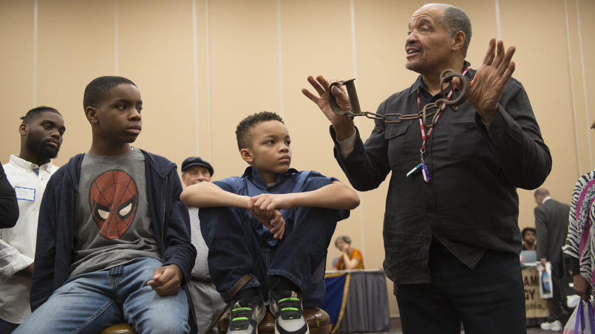 J. Justin Ragsdale holds up antique slave shackles during a demonstration on the conditions inside slave ships during the Black History and Culture Showcase in Philadelphia. (Branden Eastwood for NewsWorks)