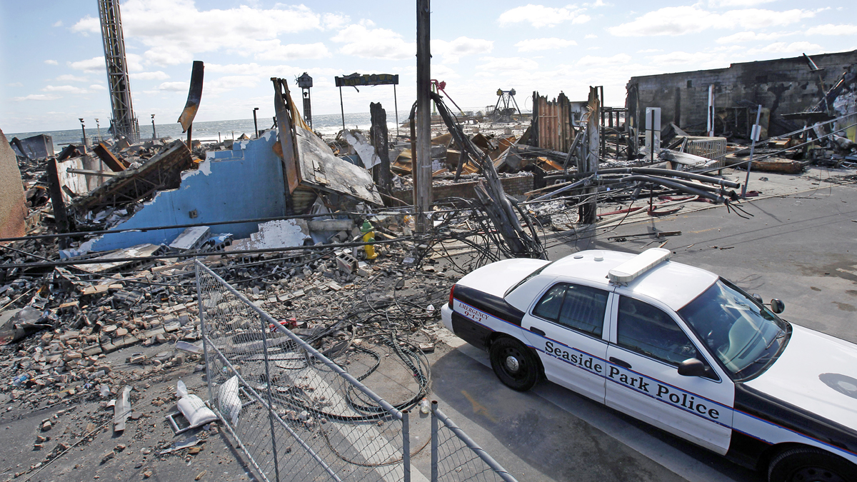 A Seaside Park police officer sits in his cruiser near the charred rubble in Seaside Park, N.J., Tuesday, Sept. 17, 2013, after a fire last Thursday that started near a frozen custard stand in Seaside Park,  quickly spread north into neighboring Seaside Heights. More than 50 businesses in the two towns were destroyed. The massive boardwalk fire in New Jersey began accidentally, the result of an electrical problem, an official briefed on the investigation said Tuesday. (AP Photo/Mel Evans)