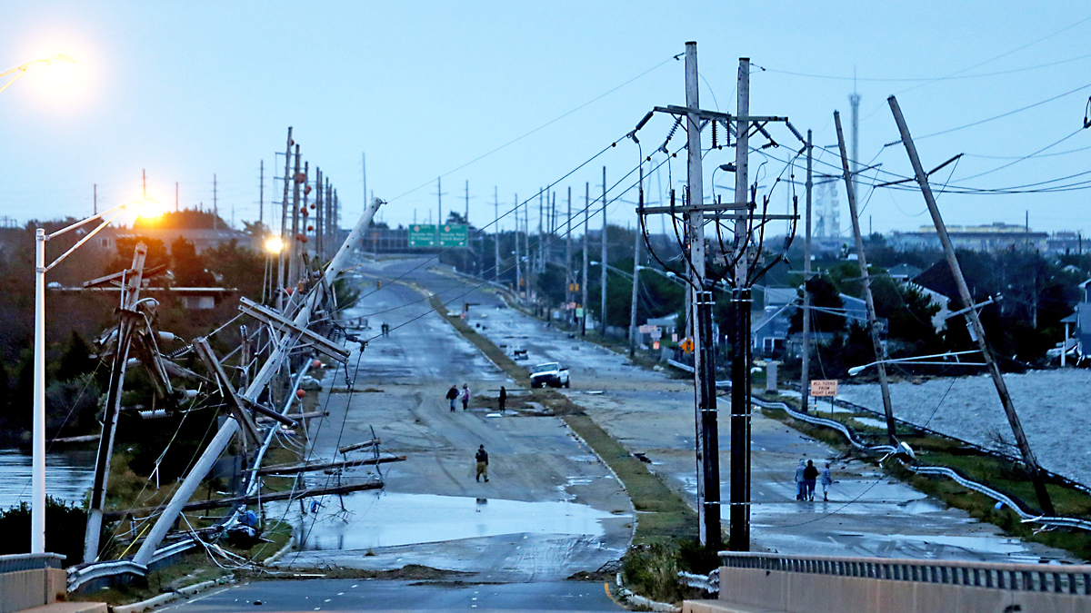 Downed power lines and a battered road is what superstorm Sandy left behind as people walk off the flooded Seaside Heights island, Tuesday, Oct. 30, 2012. (AP Photo/Julio Cortez) 