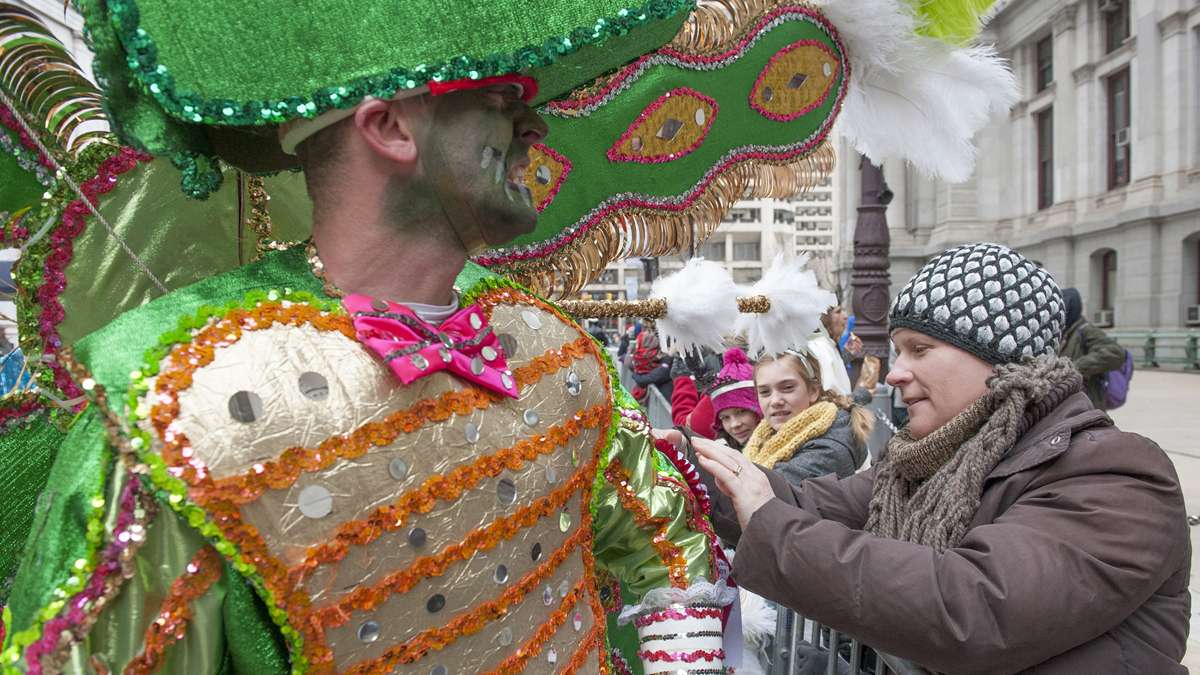 A member of the Golden Sunrise Fancy Division has a piece of their costume reattached by Elfie Beer of Spring Lake, New Jersey. (Jonathan Wilson/for NewsWorks)
