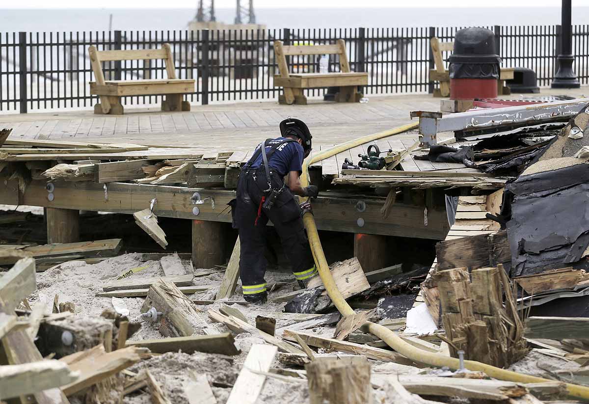  A firefighter unhooks two hoses where the the boardwalk was ripped apart to create a fire break. (AP Photo/Julio Cortez) 