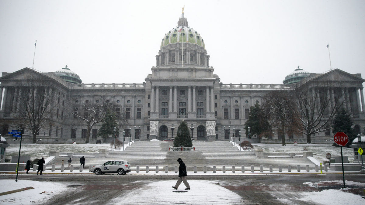 A man walks in the snow in front of the Pennsylvania Capitol in Harrisburg. The Capitol complex is in the midst of a years-long project to make roof and lighting replacements, as well as fountain repairs. (AP photo/Matt Rourke) 