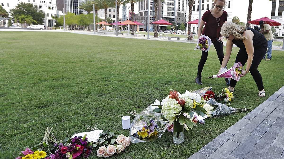 Two women place flowers for the victims of the fatal shootings at Pulse Orlando nightclub at a makeshift memorial Monday