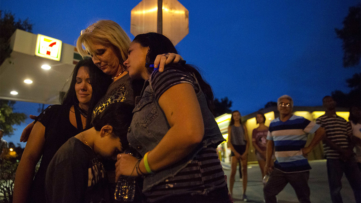  Elsie Allen, center, huddles with her daughters Jenna Allen, right, and Krista Allen-Parra, left, and her grandson Shawn Flores, all of Orlando, as they visit for the first time the scene of the Pulse nightclub mass shooting from a block away Friday, June 17, 2016, in Orlando, Fla. (AP Photo/David Goldman) 