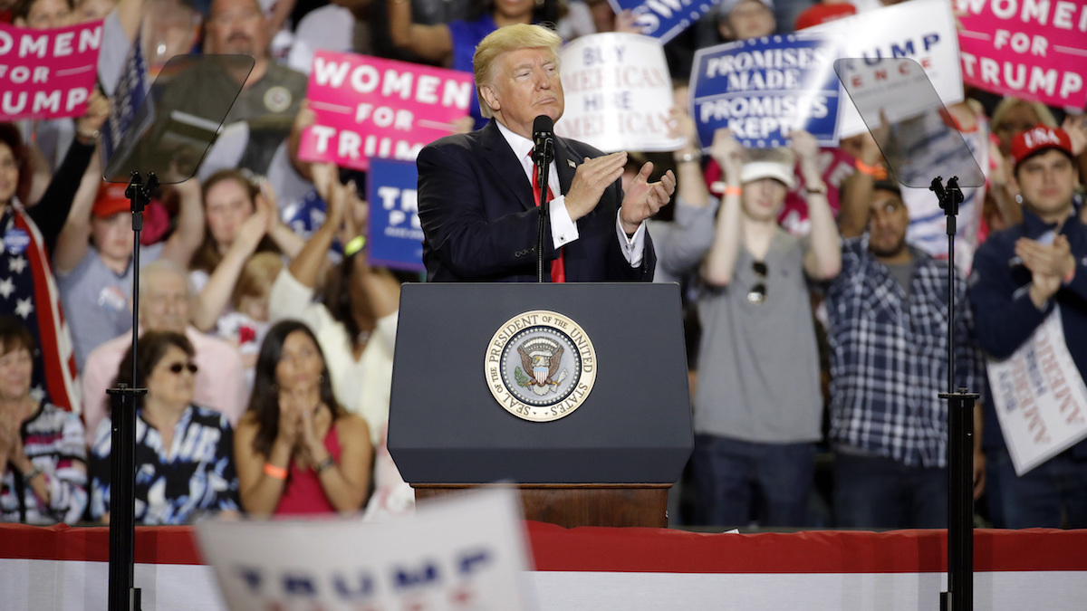 The President, clapping, at a podium