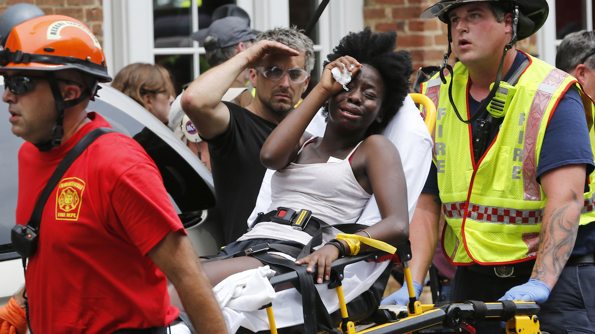 Rescue personnel help an injured woman after a car ran into a large group of protesters after an white nationalist rally in Charlottesville, Va., Saturday, Aug. 12, 2017. (AP Photo/Steve Helber)