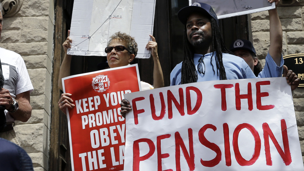 New Jersey public workers hold signs during a StateHouse rally  last year to protest Gov. Chris Christie's pension funding reductions. State lawmakers are considering a constitutional amendment to require quarterly state payments to the pension system. (AP Photo/Mel Evans)