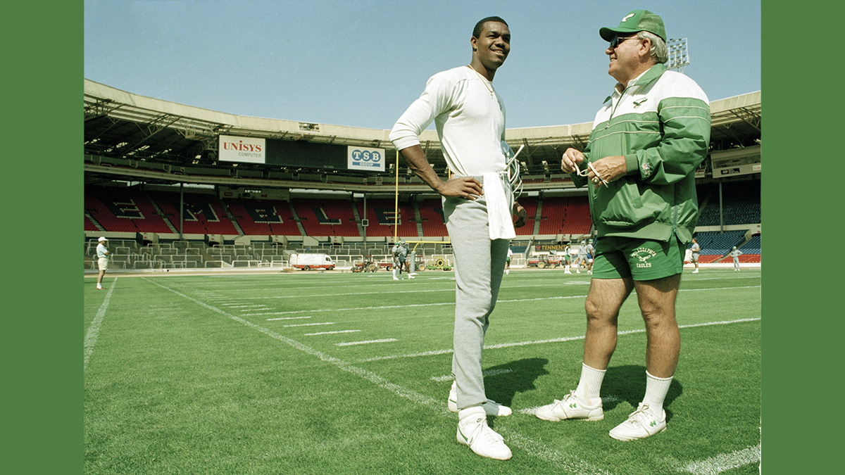  Randall Cunningham, quarterback for the Philadelphia Eagles talks with head coach Buddy Ryan during a light training session, Aug. 5, 1989, at London's Wembley Stadium where they took on the Cleveland Browns for the 1989 American Bowl. (AP Photo/Gillian Allen) 