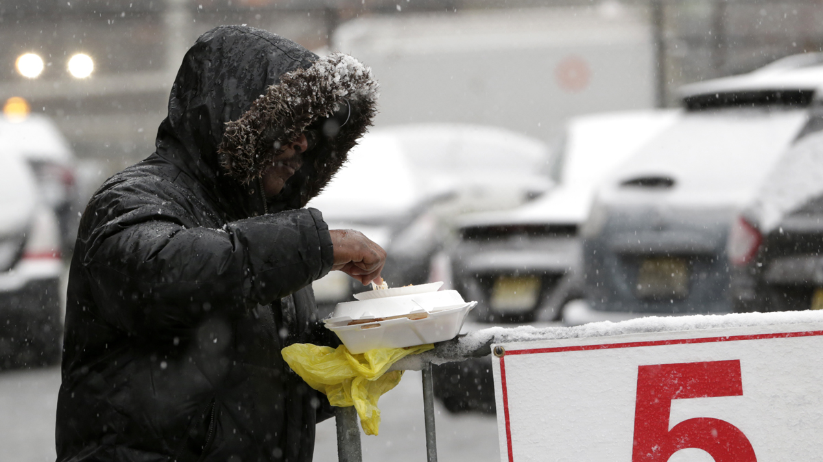 Snow falls over a homeless person while eating a pre-Thanksgiving meal from the St. John's Church soup kitchen